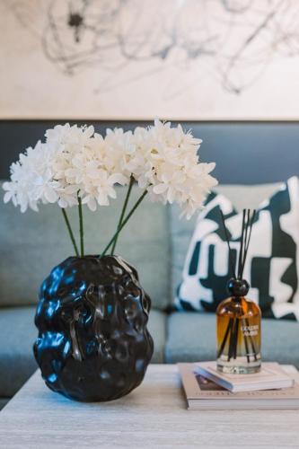 a black vase with white flowers on a table at SleepLuxury ApartHOUSE in Glasgow