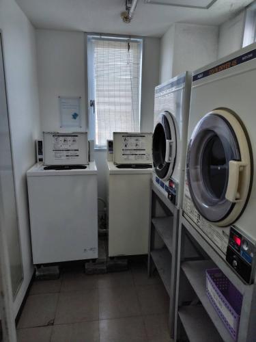 a laundry room with two washing machines and a window at パーク琴芝 in Ube