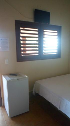 a bedroom with two windows and a white bed at Pousada da Pipa in Pipa