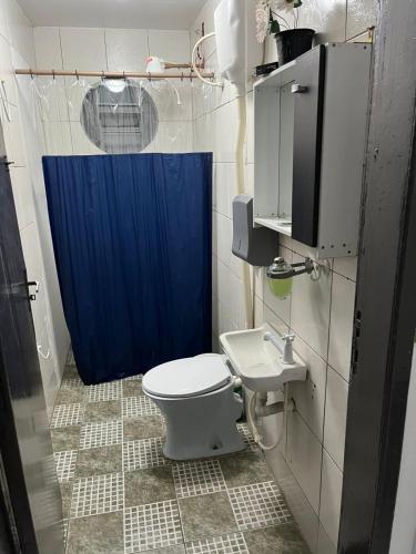 a bathroom with a toilet and a blue shower curtain at Espaço Ideal 1 com 2 Quartos in Cascavel