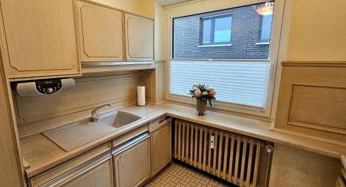 a kitchen with a sink and a window with a vase of flowers at Haus Schaper in Westerland
