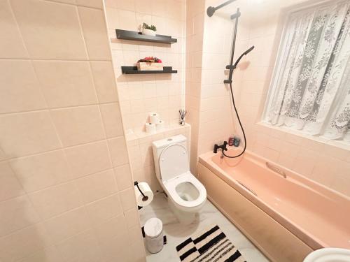 a bathroom with a toilet and a bath tub at Luton Airport Accomodation in Luton