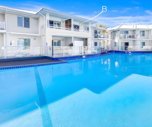 an image of a swimming pool in front of a house at Oaks Pacific Blue Resort - Studio Lagoon Apartment in Salamander Bay