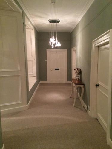 an empty hallway with a white door and a table at Trewornan Manor in Wadebridge