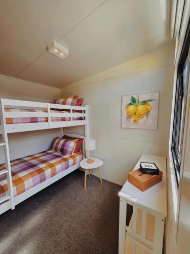 a bedroom with two bunk beds and a desk at Puriri Tiny Home in Orewa