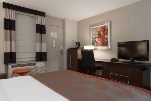 a hotel room with a bed and a desk and a television at Ramada by Wyndham Boston in Boston
