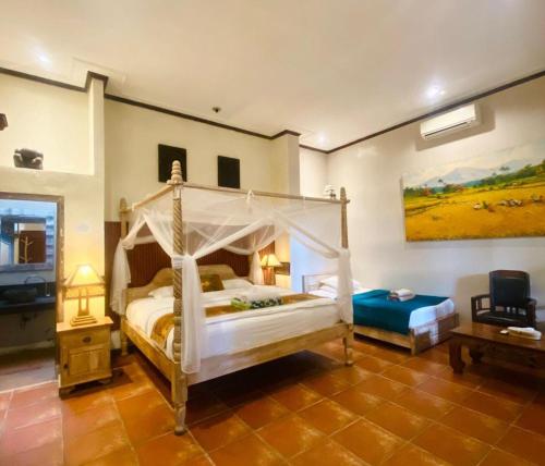 a bedroom with a white canopy bed and a table at Okawati Boutique Bungalows in Ubud