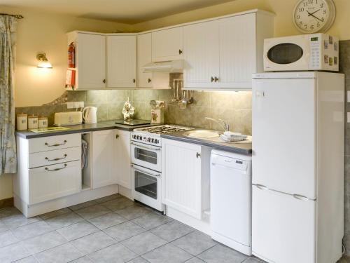 a kitchen with white cabinets and a white refrigerator at Riverside Cottage in Costessey