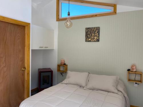a bedroom with a white bed and a window at Ruta Divisadero in Coihaique