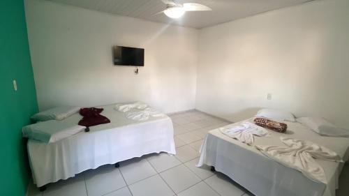 a room with two beds and a flat screen tv at Pousada e Restaurante Coração De Mãe in Prado