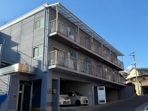 an apartment building with a car parked in front of it at BALCOM STAY Hiroshima Takasu in Hiroshima