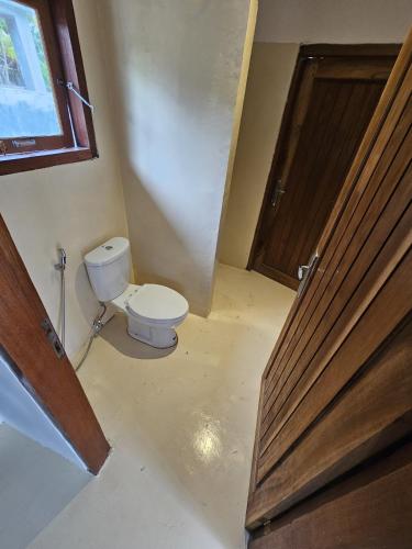 a bathroom with a toilet and a wooden door at Pangaro House in Katiet