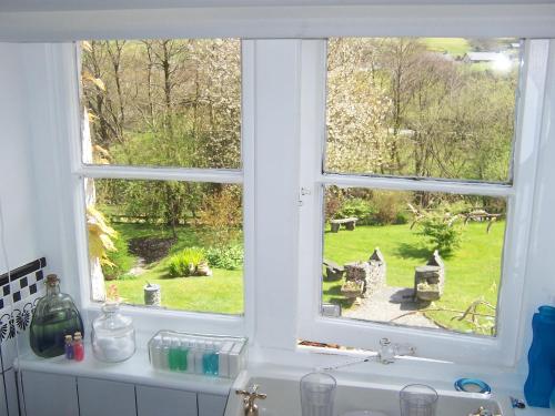 a window over a sink with a view of a garden at Penmachno Hall - self catering suite in Betws-y-coed