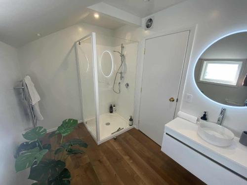 a white bathroom with a shower and a sink at Nelson Harbour View in Nelson