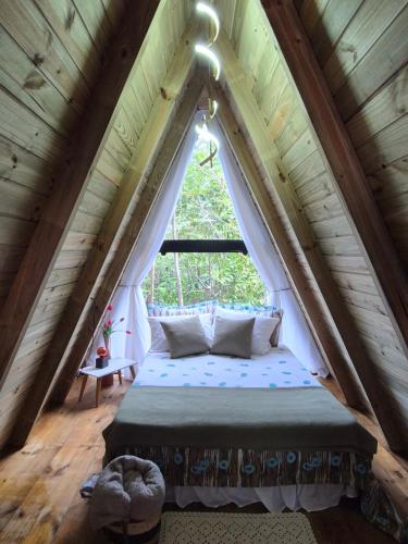 a bed in a room with a large window at Chales Holanda in Pirenópolis