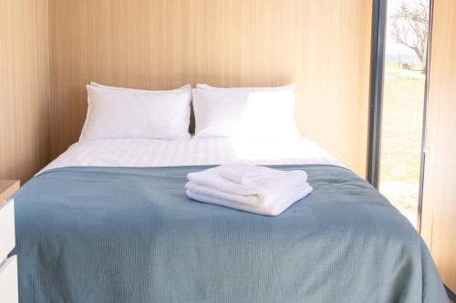 a bed with two towels sitting on top of it at Beckford Tiny House 2 by Tiny Away in Good Hope