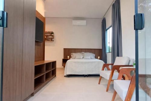 a bedroom with a bed and a flat screen tv at Chalé Vertente da Canastra in São Roque de Minas