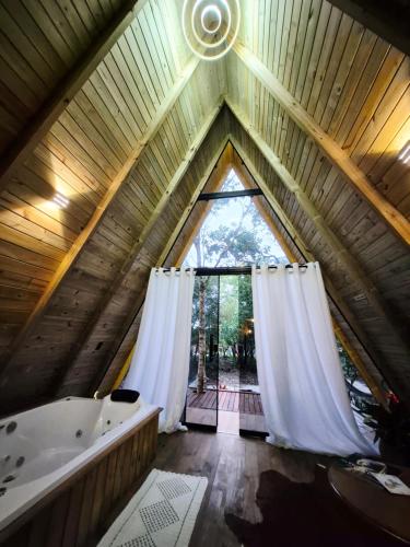 a attic bathroom with a large window and a tub at Chales Holanda in Pirenópolis