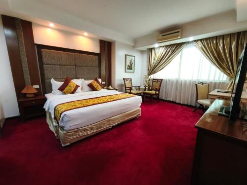 a hotel room with a large bed with a red carpet at Lido De Paris Hotel in Manila