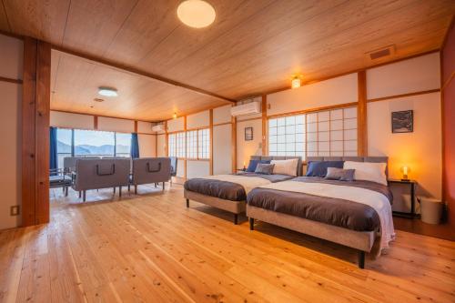 two beds in a room with wooden floors and windows at Oceanfront Up to 14 Guests BBQ Available オーシャンフロント小浜田烏 in Obama