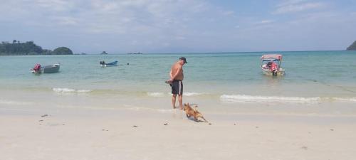 a man standing on the beach with a dog on the beach at Phu Aunna in Ko Phayam