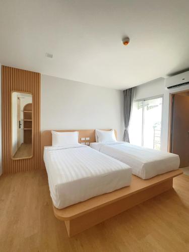 a bedroom with two beds and a large window at Wynora Hotel in Klong Toi
