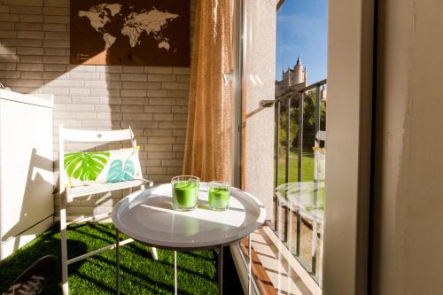 a table on a balcony with two glasses on it at El Mirador Del Alcazar in Segovia