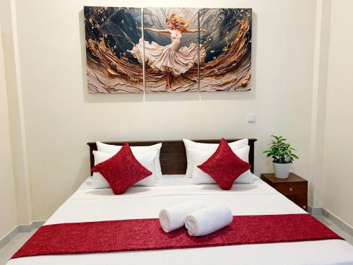 a bed with red pillows and a painting on the wall at Blessora Sky Retreat in Kalutara