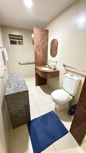 a bathroom with a white toilet and a blue rug at Comfortable house in Natal in Natal