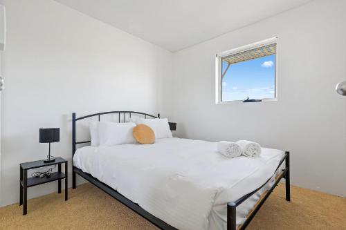 a bedroom with a bed with white sheets and a window at ParkView on Owen in Huskisson