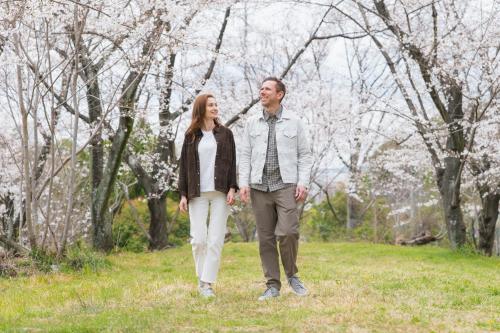 a man and a woman walking in a field with trees at Apartment Hotel DIG the OSAKA in Suita