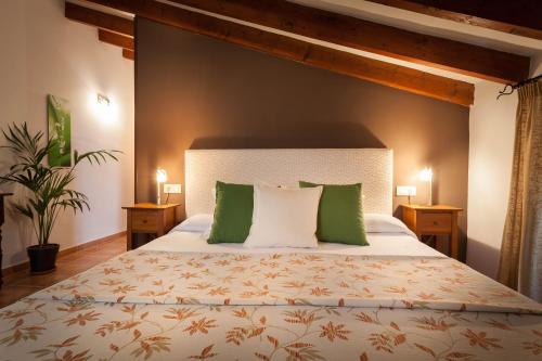 sypialnia z dużym łóżkiem z zielonymi i białymi poduszkami w obiekcie Petit Hotel Alaro w mieście Alaró