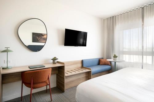a hotel room with a bed and a desk and a mirror at Quest Townsville on Eyre in Townsville