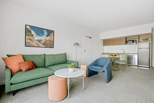 a living room with a green couch and a table at Quest Townsville on Eyre in Townsville