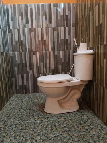 a toilet in a bathroom with a wall at Queen Rinjani Stay & Café in Sembalun Lawang