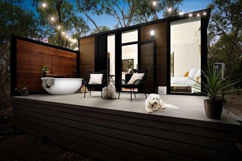 a white dog laying on a wooden deck with a bedroom at HeartStone Hill by Tiny Away in Castlemaine