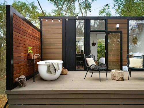 a large tub sitting on a deck with a house at HeartStone Hill by Tiny Away in Castlemaine