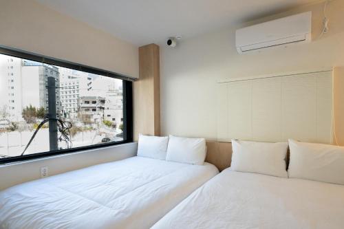 two beds in a room with a large window at Trip made in Busan