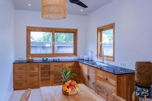 a kitchen with wooden cabinets and a sink and a table at Villa Jati Private Pool - Amed in Amed