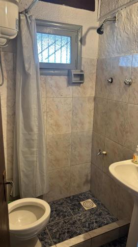 a bathroom with a toilet and a sink and a window at Los Rochas, Barra de Chuy in Barra del Chuy