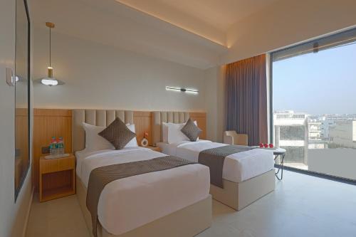 two beds in a hotel room with a large window at Sterling Avante Chandigarh Mohali in Mohali