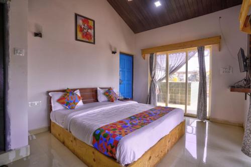 a bedroom with a bed and a large window at Hotel Padma in Morjim