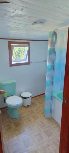 a bathroom with a toilet and a tub and a window at Alojamiento Los Canelos in Ancud