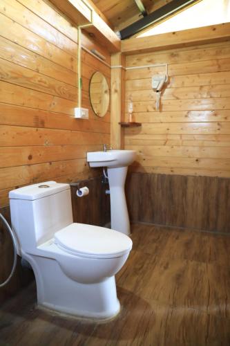 a bathroom with a white toilet and a sink at Therpup Resort in Bangalore