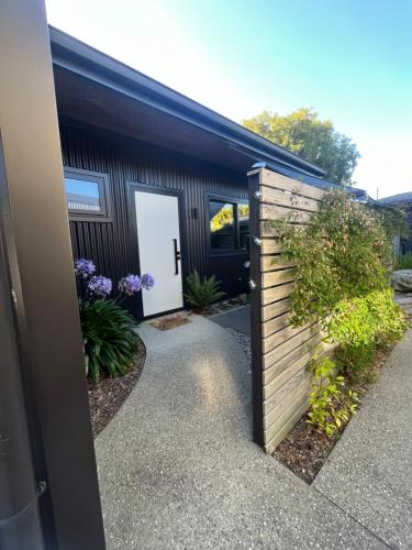 a building with a white door and a fence at East Rock - Cosy Guesthouse in Kelvin Heights in Queenstown