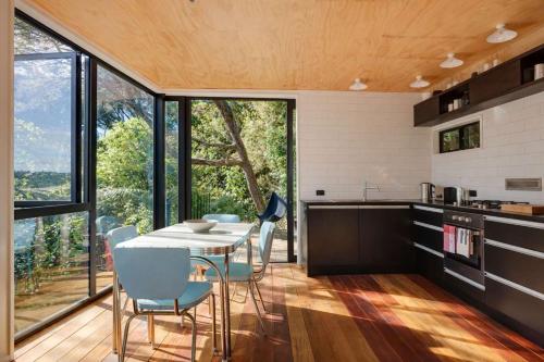 a kitchen and dining room with a table and chairs at Blackpool House - Stay Waiheke in Oneroa