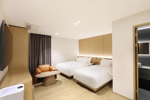 a hotel room with two beds and a chair at 부천 브라운도트 호텔 부천역점 in Sosa