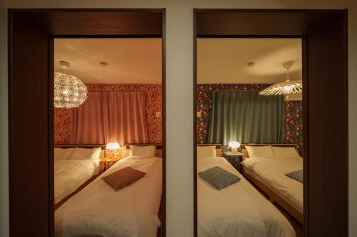 a bedroom with two beds and two mirrors at LilyHouse in Beppu