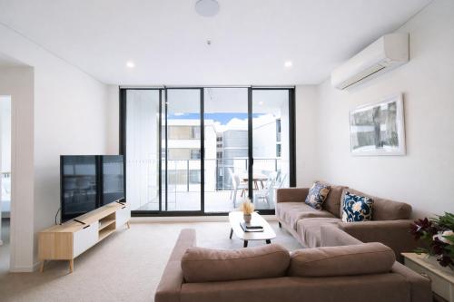 a living room with a couch and a tv at Spacious cozy2BR close to OlympicPark free carpark in Sydney