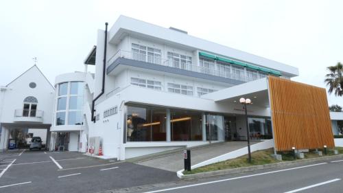 a large white building with a parking lot at Amakusa Santacoming Hotel in Amakusa